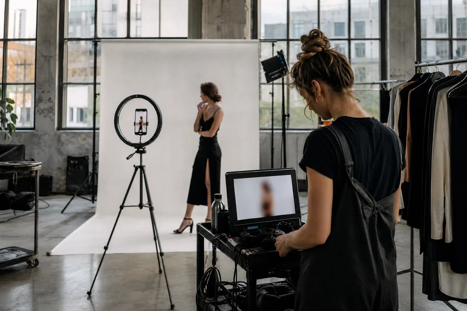 Dzień zdjęciowy w warszawskim studiu, dorosła modelka nagrywa pionowe wideo telefonem na statywie z lampą pierścieniową